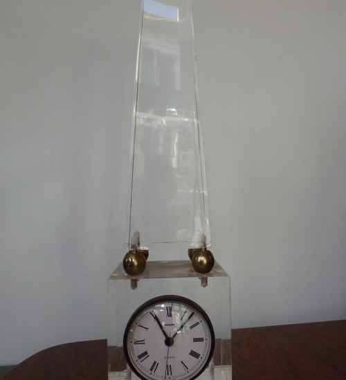 Pyramide de plexiglas enserrant une horloge.