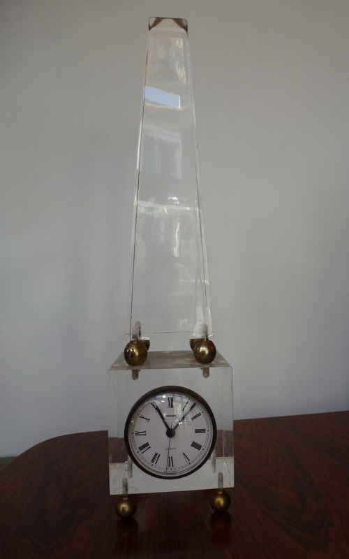 Pyramide de plexiglas enserrant une horloge.